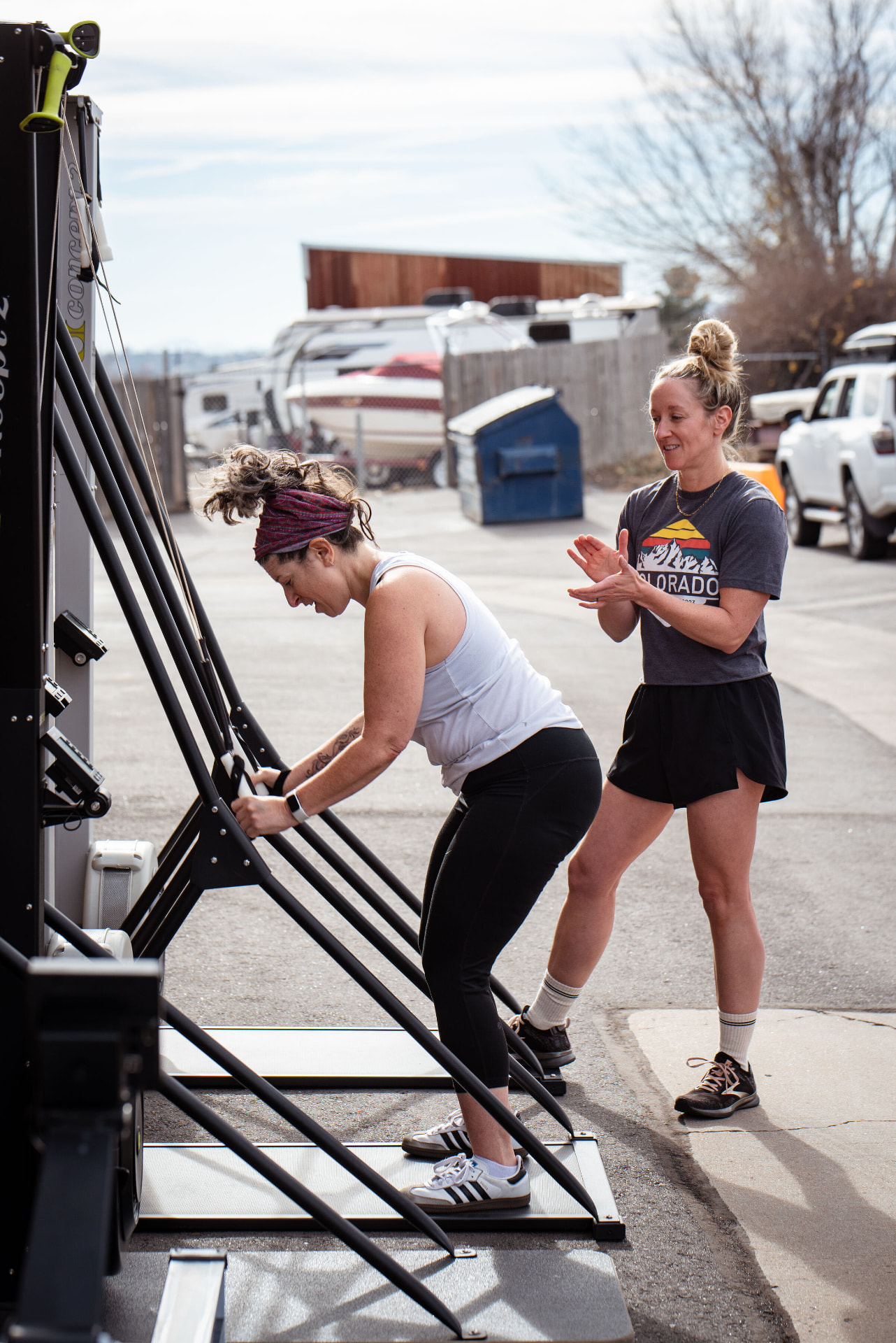 A woman training on a ski erg with her coach cheering her on