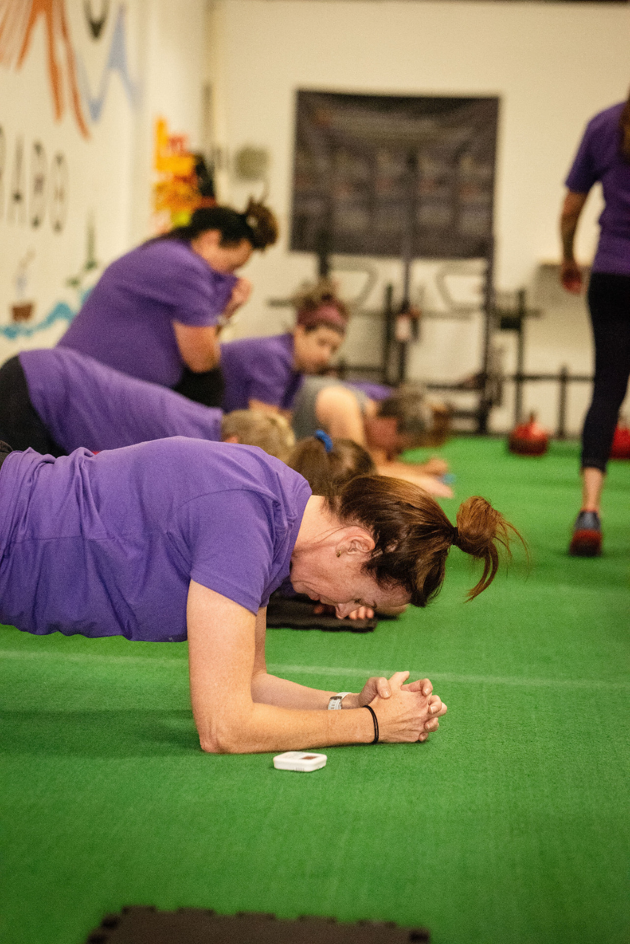 A group of women holding planks together on the turf at Ethos Colorado