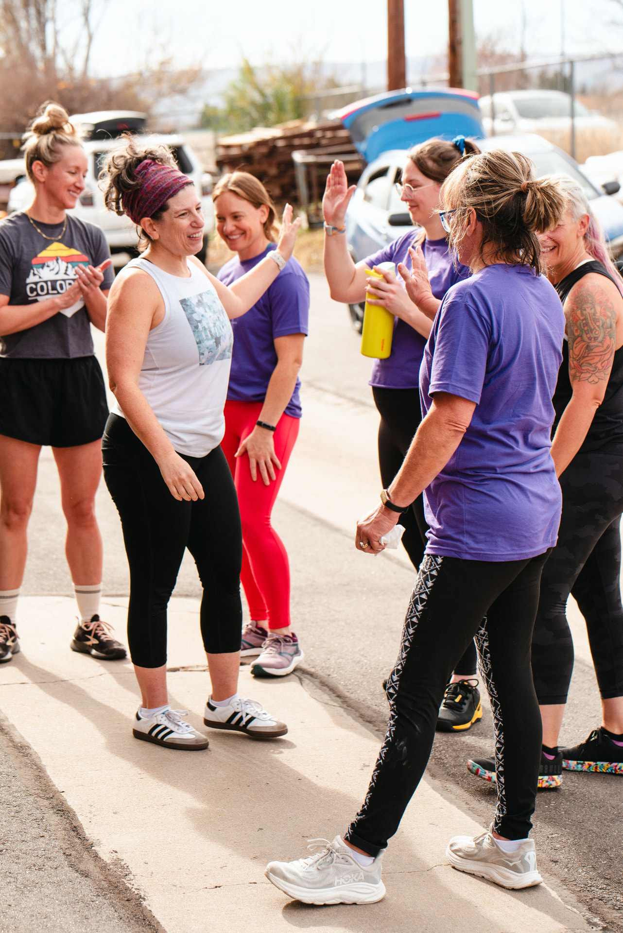 Women high-fiving after a group workout outside Ethos Colorado