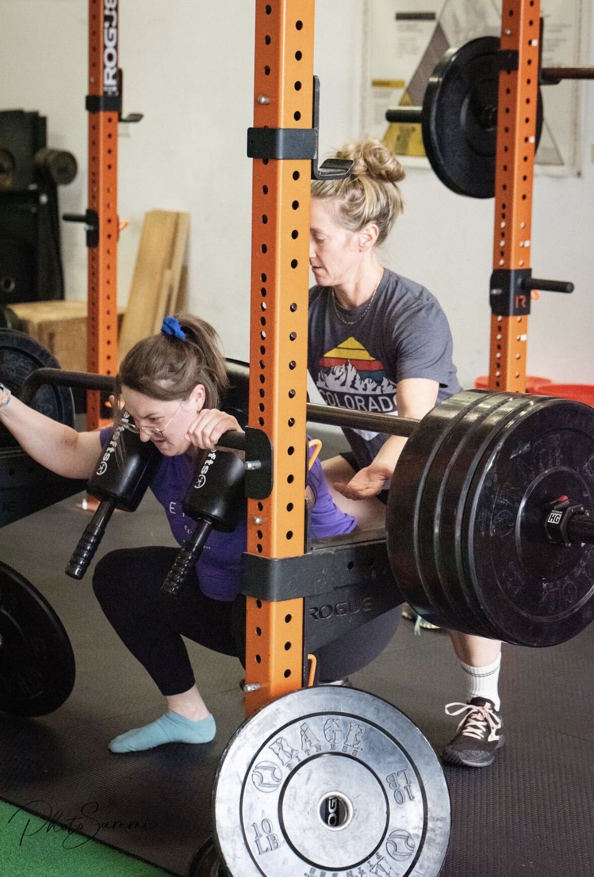 An Ethos Colorado coach spotting a member through a barbell squat